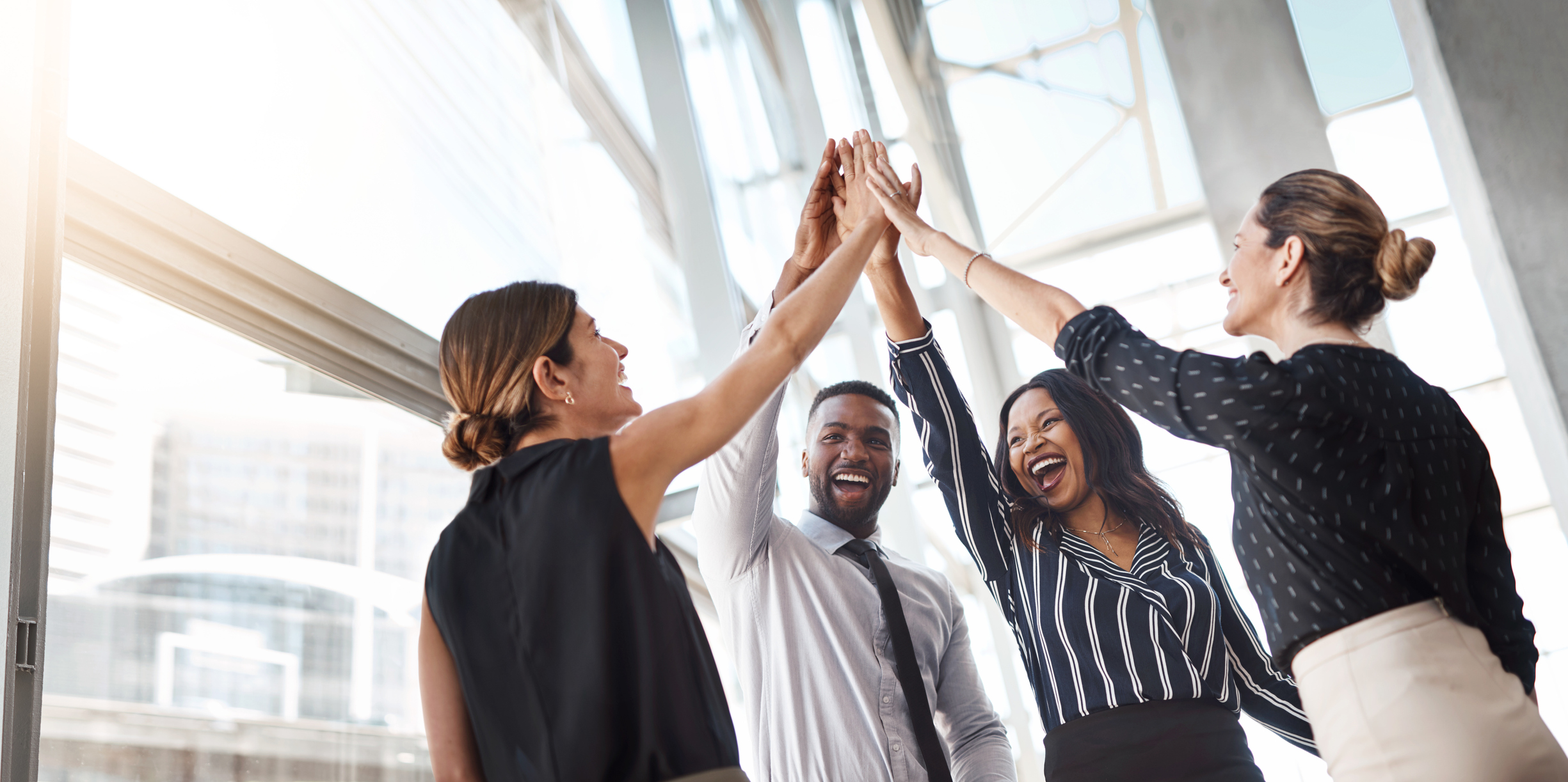Shot of a group of professional businesspeople high fiving in the office